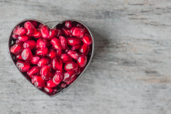 Pomegranate seeds in a heart shaped container.