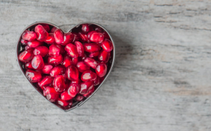 Pomegranate seeds in a heart shaped container.