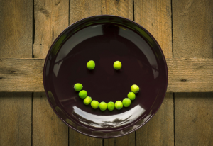 Vegetables on a plate in the form of a smiley face.