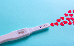 A pregnancy test next to cut out hearts.