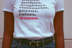 A person wearing a shirt with the text: friends. mothers. daughters. visionaries. queens. rulers. women.