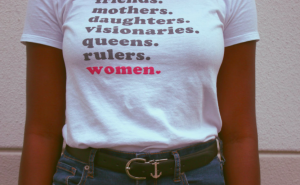 A person wearing a shirt with the text: friends. mothers. daughters. visionaries. queens. rulers. women.