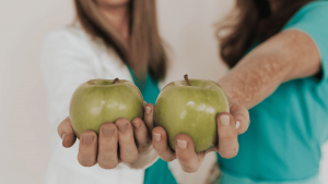 Two naturopaths, each holding an apple.