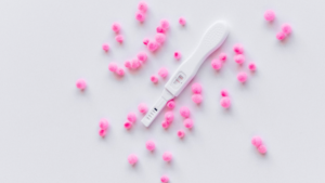 A pregnancy test surrounded by pom poms.