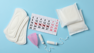 An open menstrual pad, packaged menstrual pad, tampon and menstruation cup with a calendar with 4 days crossed off in red pen