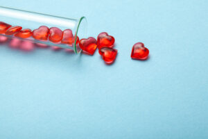 Hearts and test tube. Baby from tube vitro glass. Artificial insemination, IVF. Blue background..